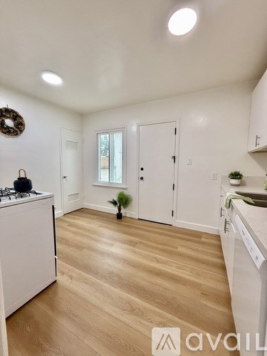 A kitchen with white cabinets and a wooden floor.