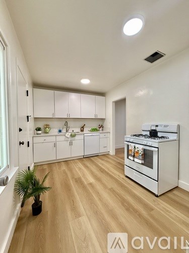 A kitchen with white cabinets and a wooden floor.