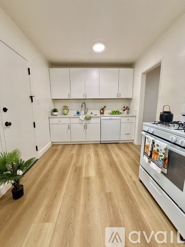 A kitchen with white cabinets and a wooden floor.