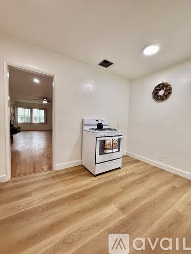 A kitchen area with a white oven and wooden flooring.