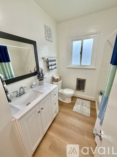 A bathroom with a sink, toilet, and mirror.