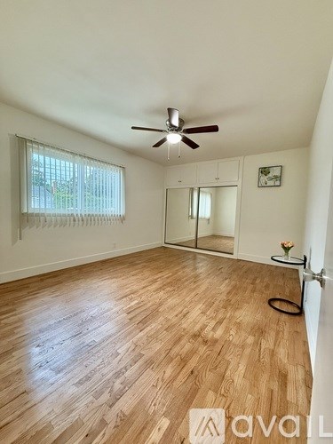 A room with wooden flooring and a ceiling fan.