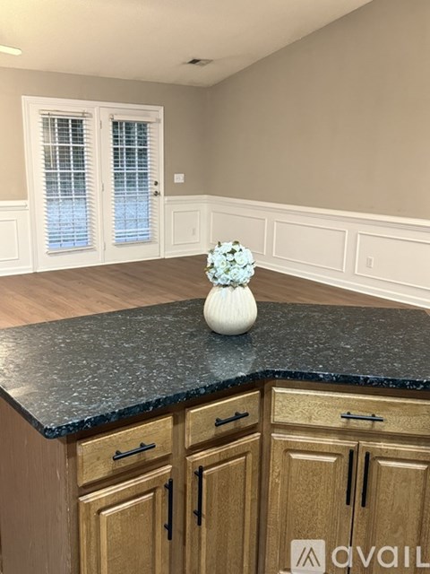 A kitchen counter with a vase on it and wooden cabinets.