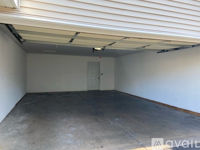 A spacious garage with a concrete floor and a white door.