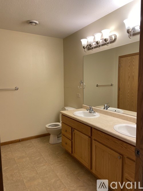 A bathroom with a toilet, sink, and mirror.