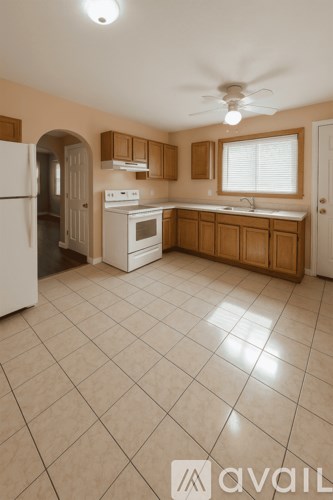 A kitchen with a white refrigerator, a white stove, and wooden cabinets.