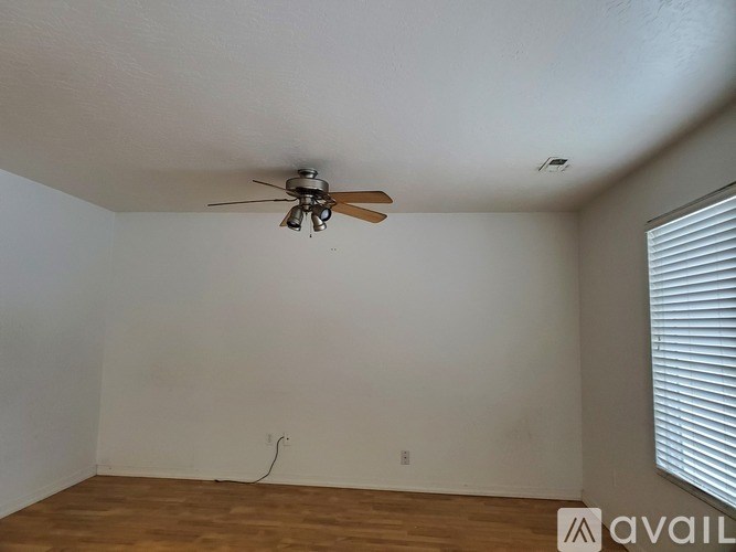 A room with a ceiling fan and wooden flooring.