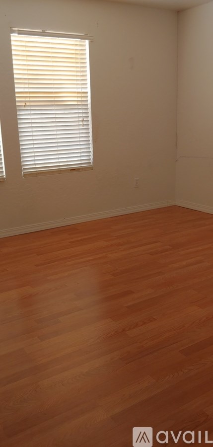 A room with wooden flooring and a window with blinds.