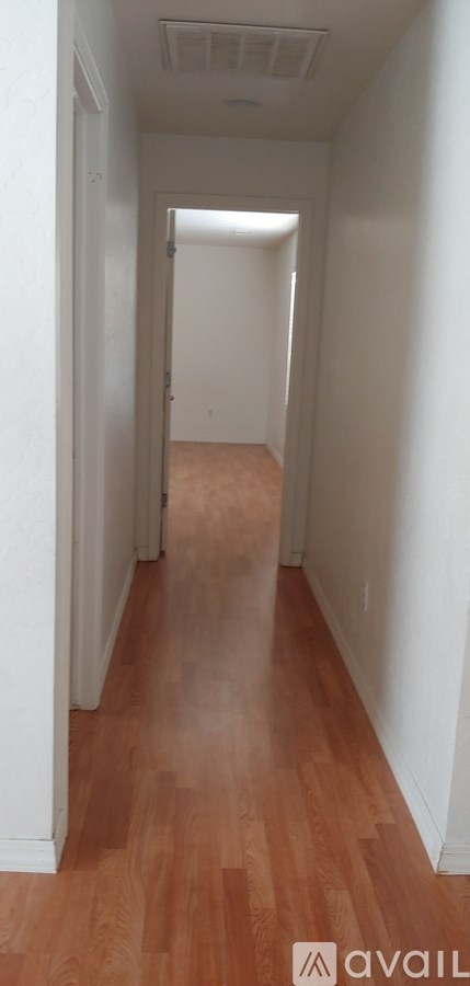 A long hallway with wood floors and white walls.