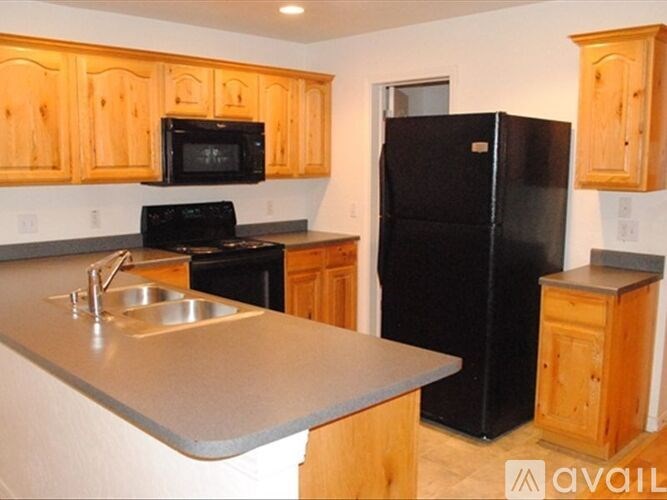 A kitchen with a black refrigerator and wooden cabinets.