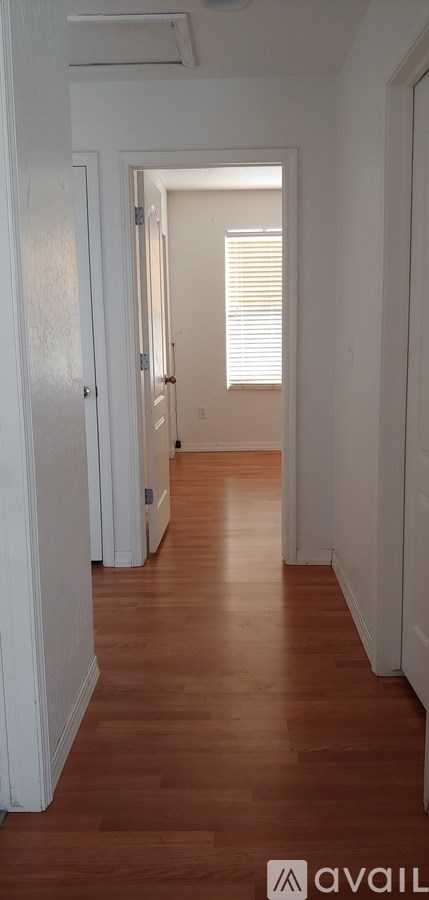 A hallway with wooden floors and white walls.