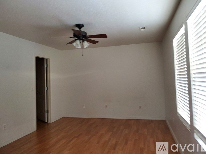 A room with a ceiling fan and wooden flooring.