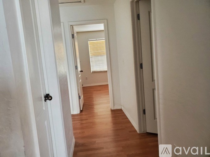 A hallway with wooden floors and white walls.