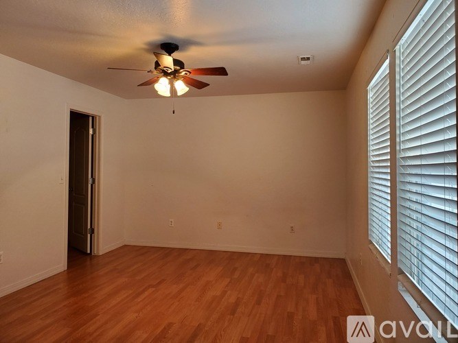 A room with a ceiling fan and wooden flooring.