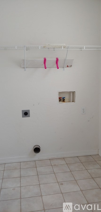 A white wall with a small hole and a white shelf above it.