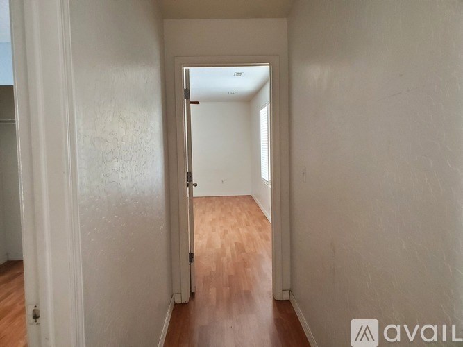 A hallway with a wooden floor and white walls.