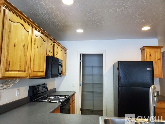 A kitchen with wooden cabinets and black appliances.