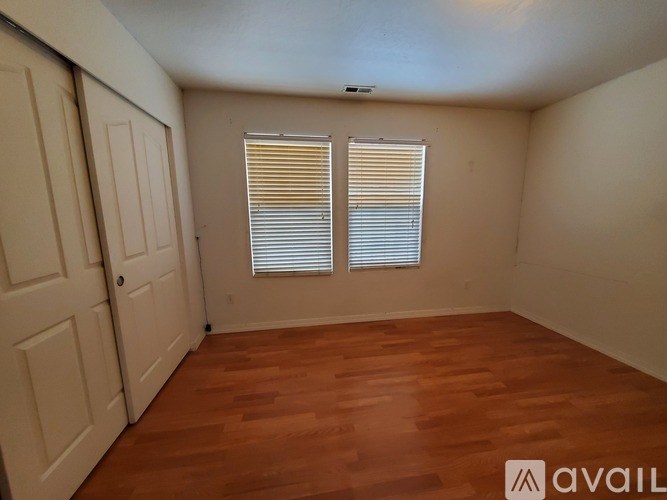 A room with wooden flooring and a window with blinds.