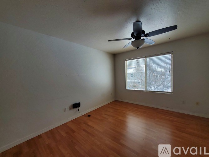 Empty room with a ceiling fan and wooden flooring.