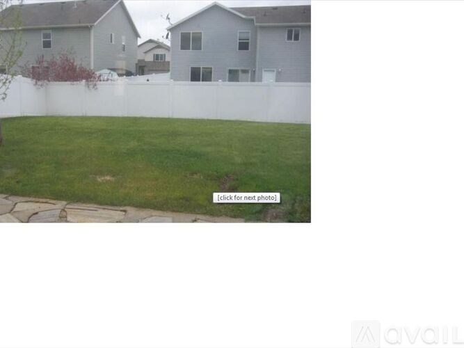 A grassy area with a white fence and a house in the background.