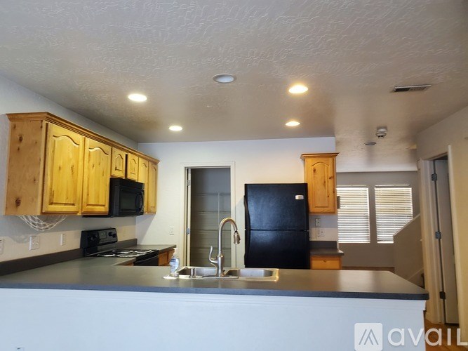 A kitchen with wooden cabinets and a black refrigerator.