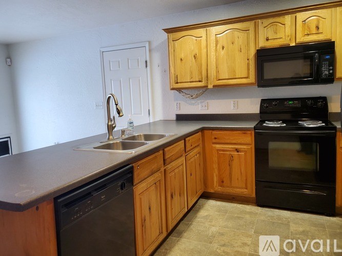 A kitchen with wooden cabinets and black appliances.