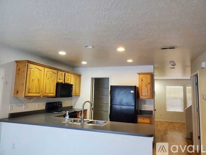 A kitchen with wooden cabinets and a black fridge.