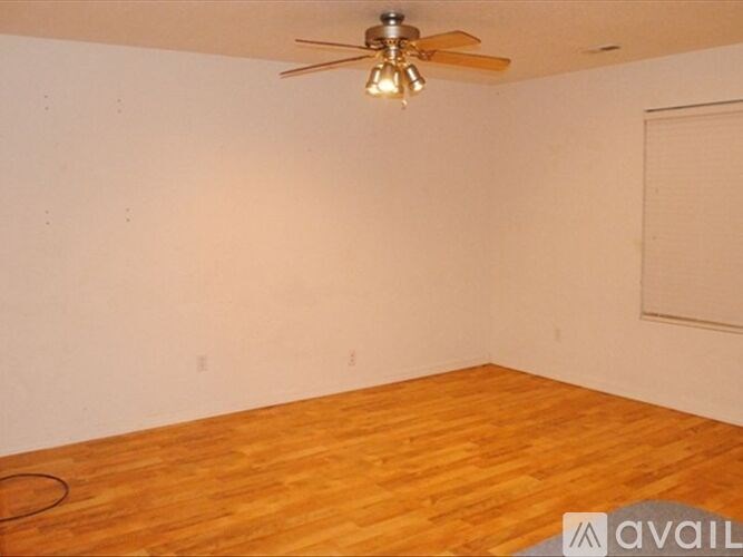A room with a ceiling fan and wooden flooring.