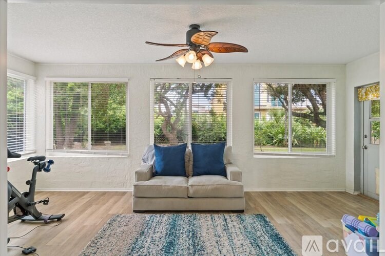 A living room with a couch, a fan, and a rug.