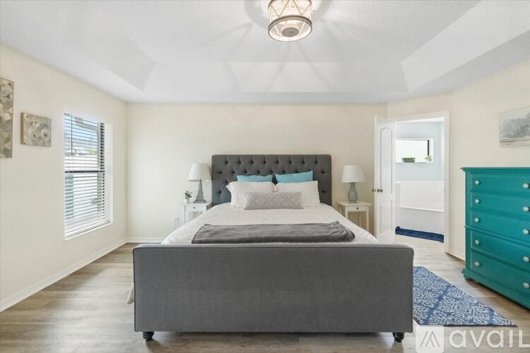 A bedroom with a large bed and a teal dresser.