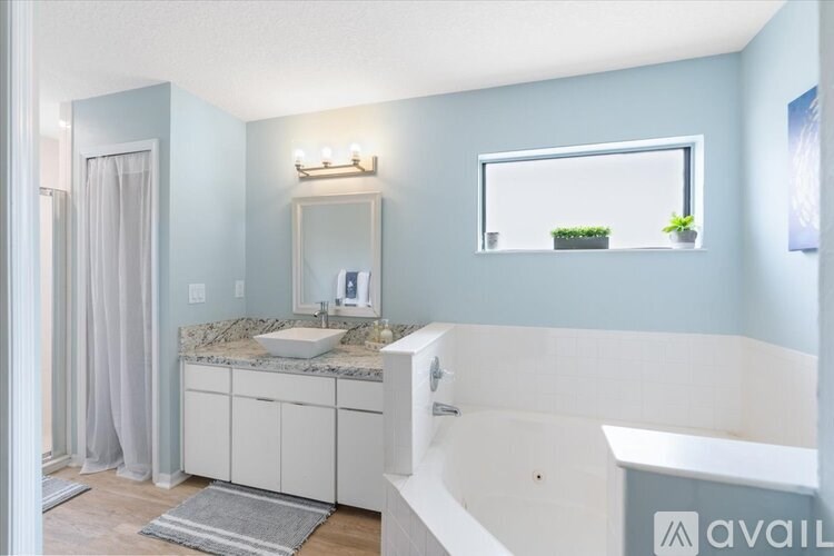 A bathroom with a sink, mirror, and bathtub.