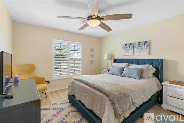 A bedroom with a bed, a chair, and a ceiling fan.