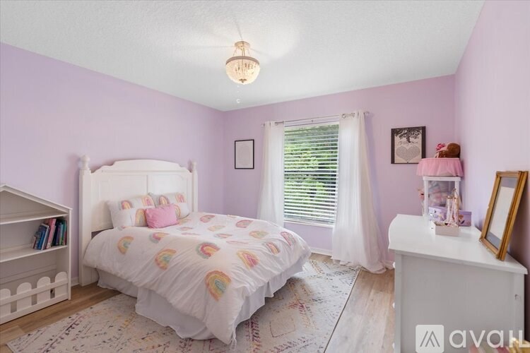 A bedroom with a white bed and a pink wall.