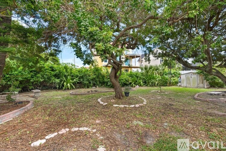 A backyard with a tree and a circular design made of stones.