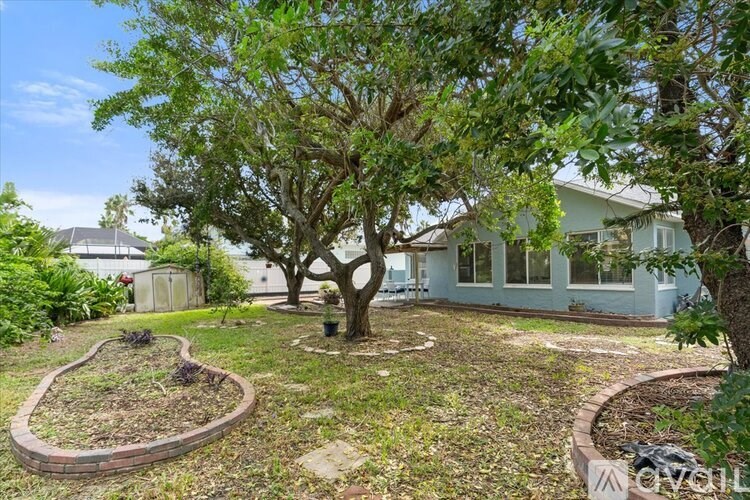 A tree in a backyard with a house in the background.