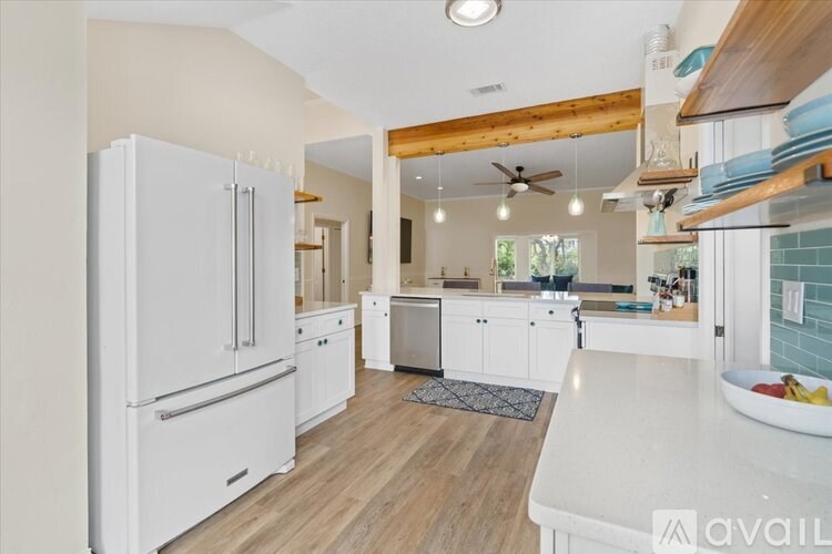 A kitchen with white appliances and wooden floors.