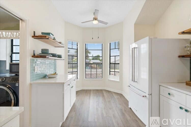 A kitchen with white cabinets and a ceiling fan.