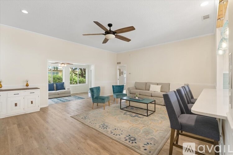 A living room with a ceiling fan and a rug on the floor.