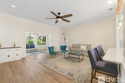 A living room with a ceiling fan and a rug on the floor.