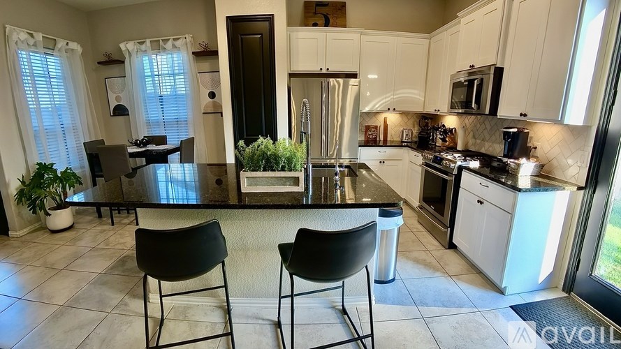 A kitchen with black chairs and a black counter top.