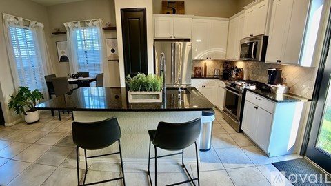 A kitchen with black chairs and a black counter top.