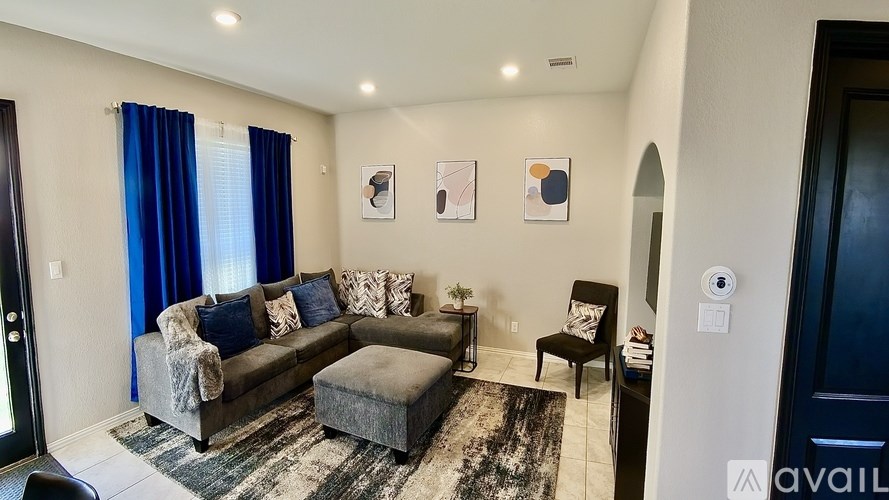 A living room with a grey couch, a small ottoman, and a rug.
