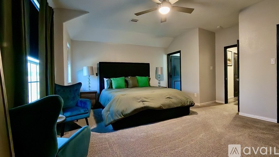A bedroom with a bed, chair, and ceiling fan.