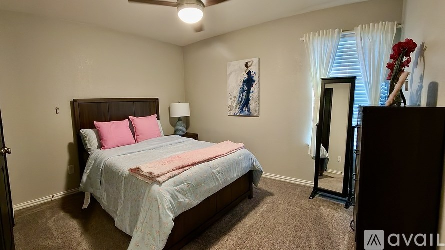 A bedroom with a bed, a ceiling fan, and a painting on the wall.