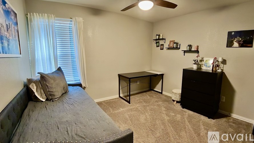 A bedroom with a bed, a dresser, and a ceiling fan.