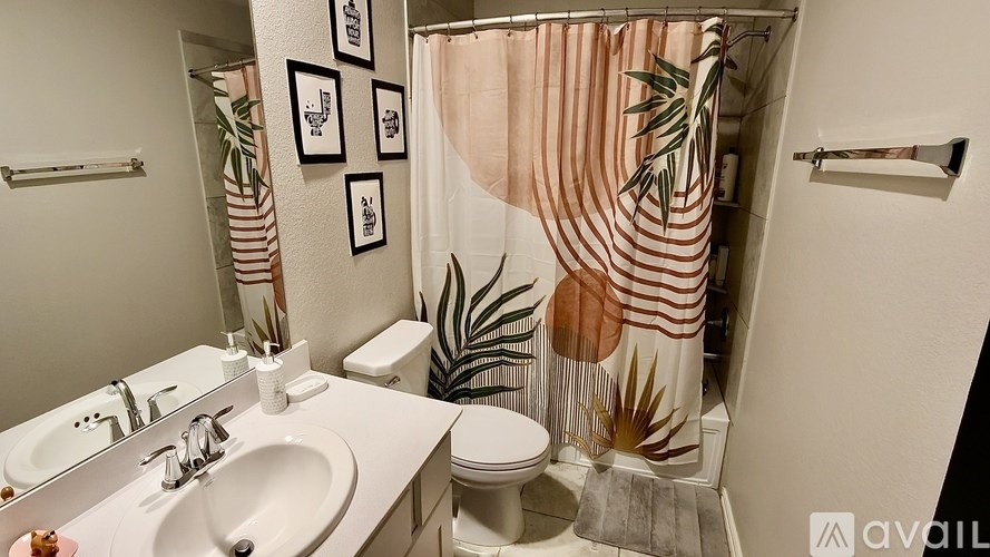 A bathroom with a sink, toilet, and a shower curtain with a leaf design.