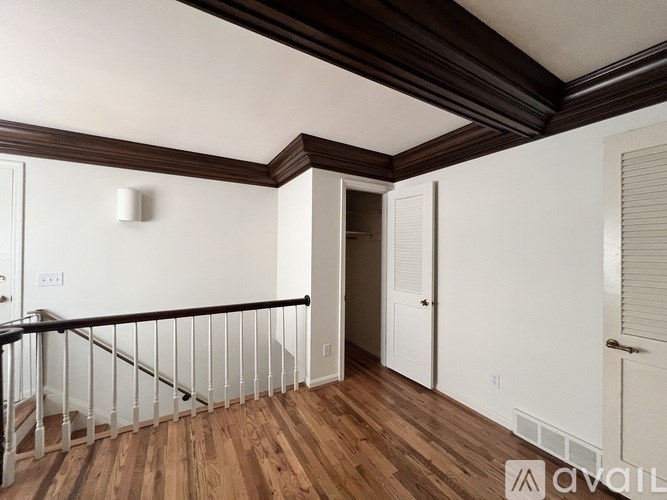 A room with wooden floors and white walls, with a balcony on the left side.