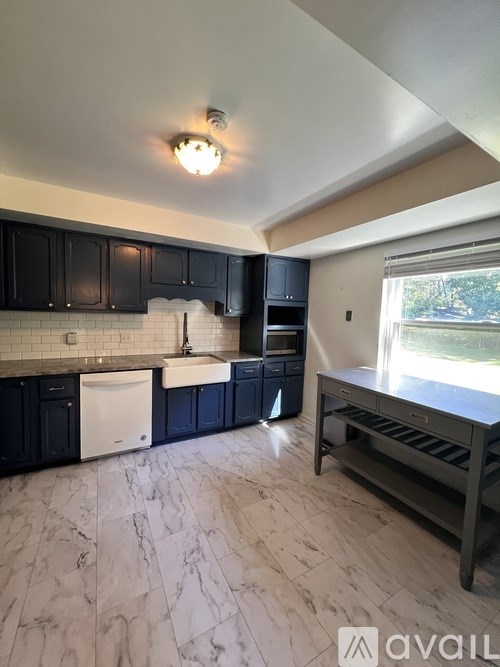 A kitchen with black cabinets and a white dishwasher.