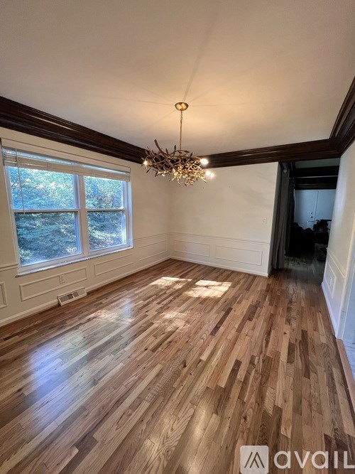 A room with wooden flooring and a chandelier.