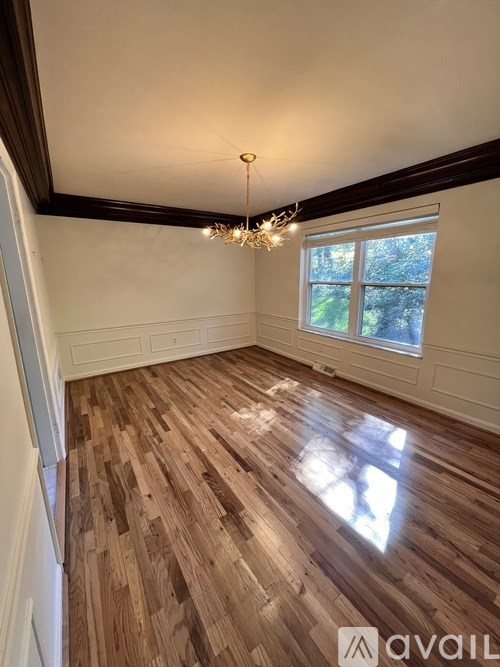 A room with wooden flooring and a chandelier hanging from the ceiling.